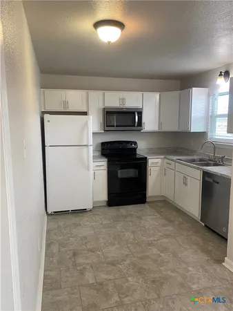 a kitchen with a sink a stove a microwave and a refrigerator
