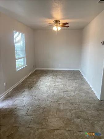 en empty room with windows and chandelier fan