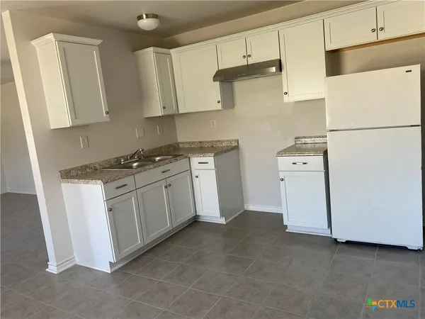 a kitchen with granite countertop white cabinets and white appliances
