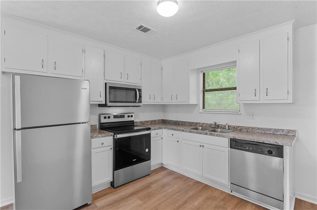 340 Tanglewood Drive, Unit A Monroe, GA 30656 - Photo 7 of 17 a kitchen with granite countertop white cabinets and white appliances