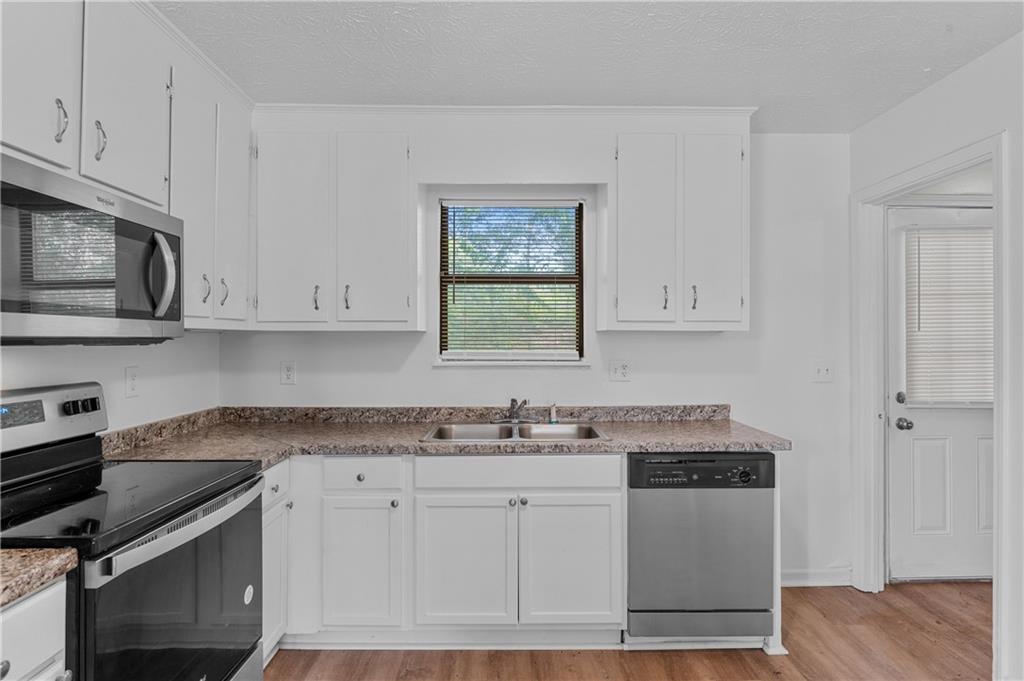 340 Tanglewood Drive, Unit A Monroe, GA 30656 - Photo 8 of 17 a kitchen with stainless steel appliances granite countertop a stove a sink and white cabinets