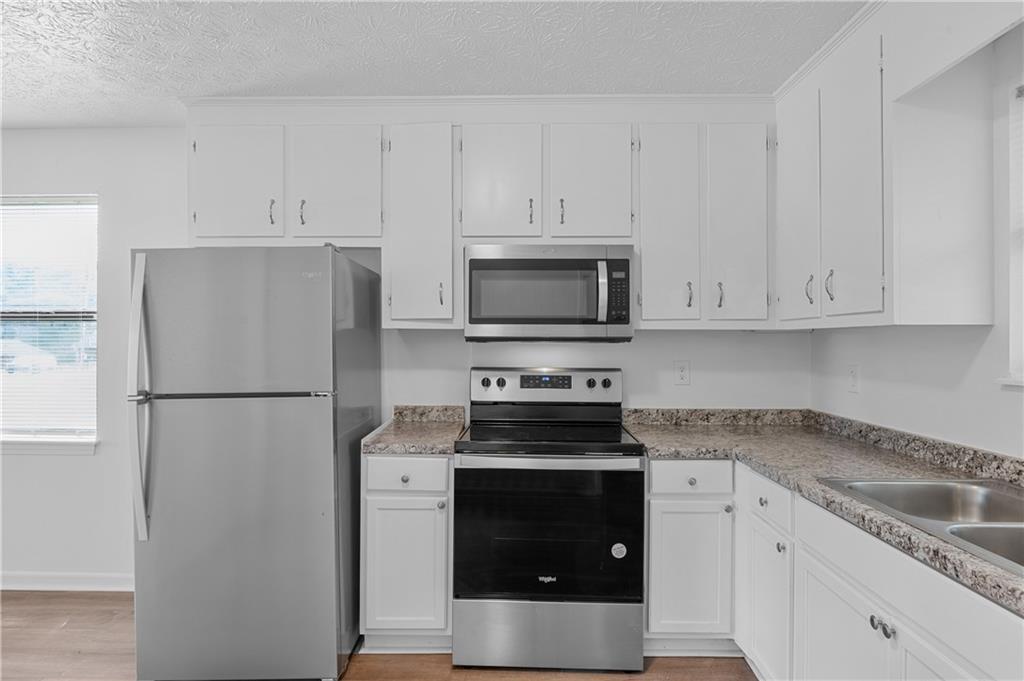340 Tanglewood Drive, Unit A Monroe, GA 30656 - Photo 9 of 17 a kitchen with white cabinets and stainless steel appliances
