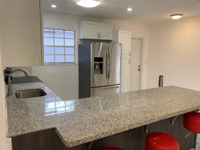 a kitchen with kitchen island a counter top space a sink a refrigerator and wooden cabinets
