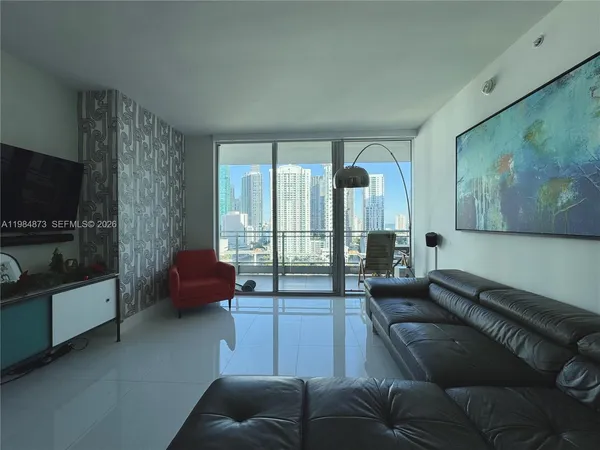 a living room with furniture a flat screen tv and a floor to ceiling window