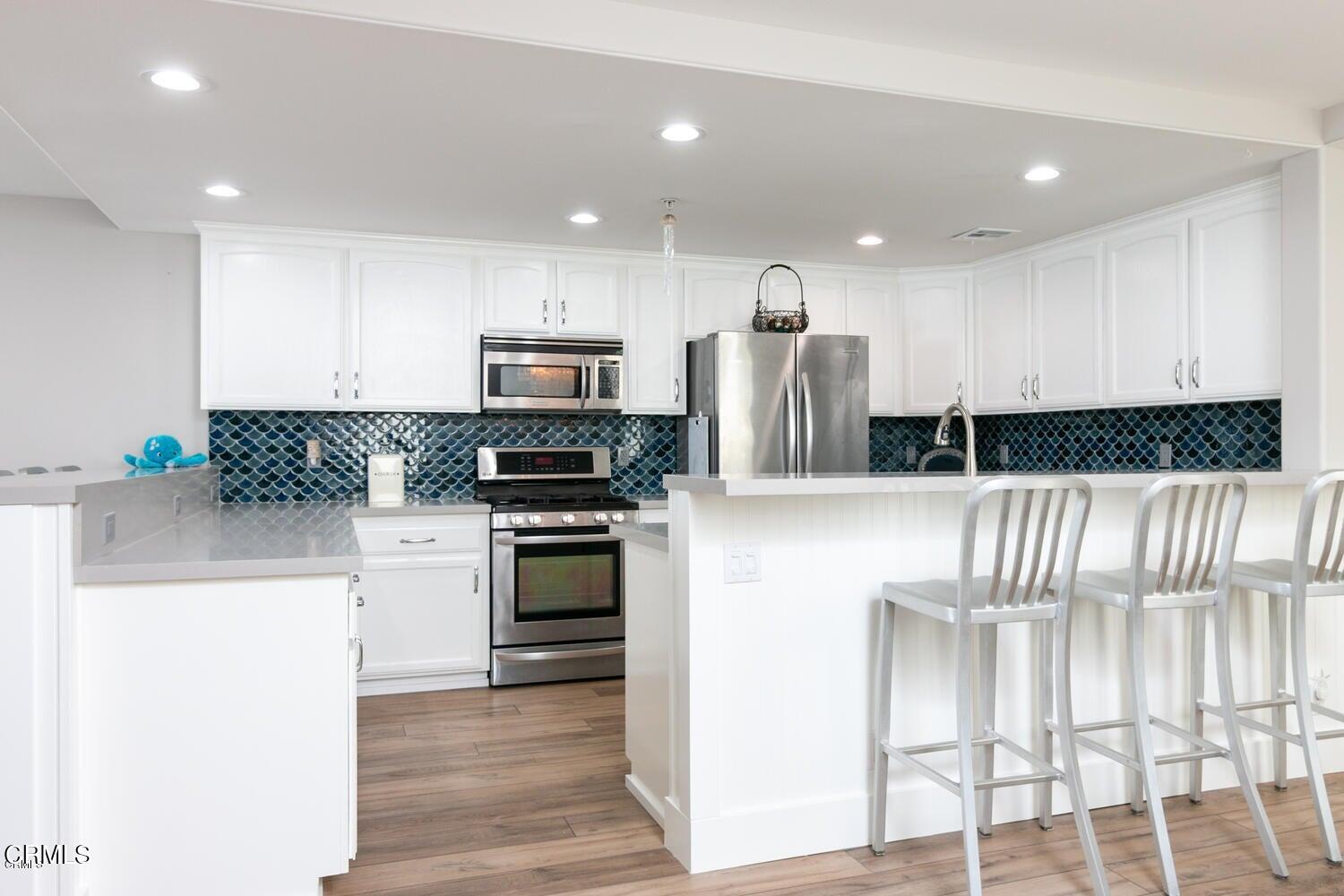 925 Dunes Street Oxnard, CA 93035 - Photo 5 of 27 a kitchen with kitchen island granite countertop a stove top oven a sink a refrigerator and white cabinets with wooden floor