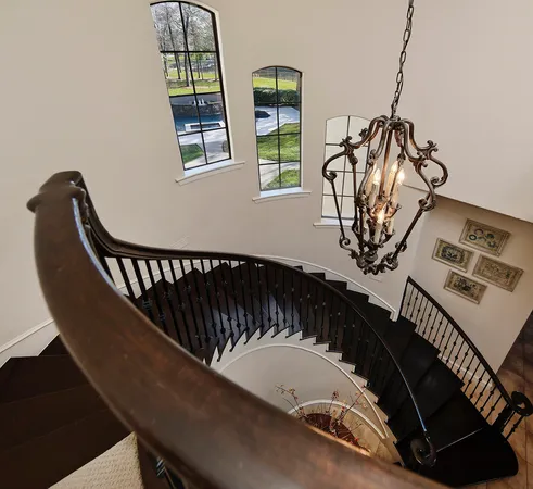 a view of staircase with railing and a chandelier