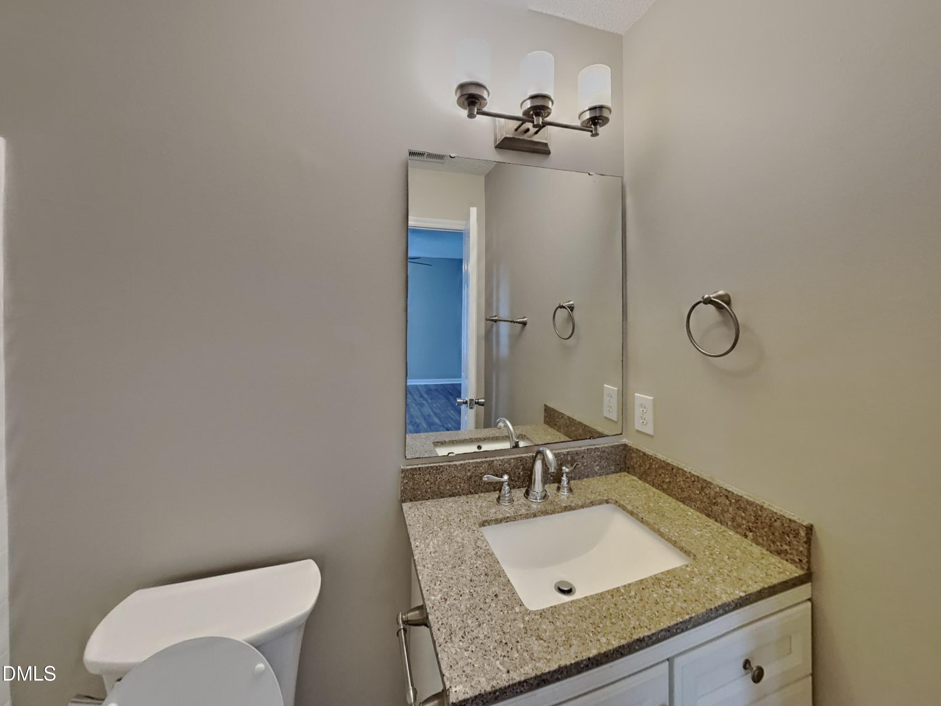 5516 Wilhagan Court Raleigh, NC 27616 - Photo 8 of 16 a bathroom with a granite countertop sink a toilet and mirror