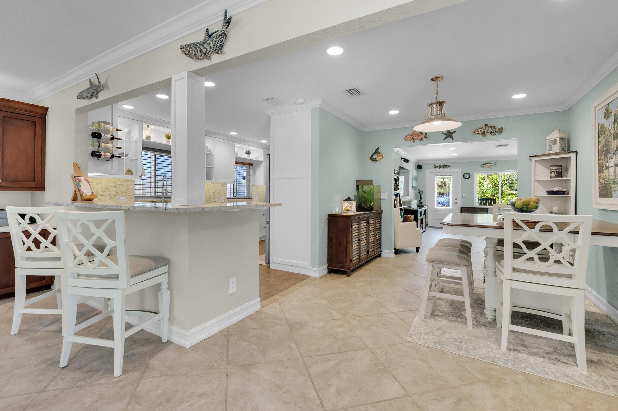 548 Northwest 55th Street Boca Raton, FL 33487 - Photo 10 of 33 a kitchen with stainless steel appliances kitchen island granite countertop a table chairs sink and cabinets