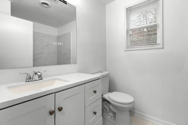 a bathroom with a toilet sink vanity and mirror