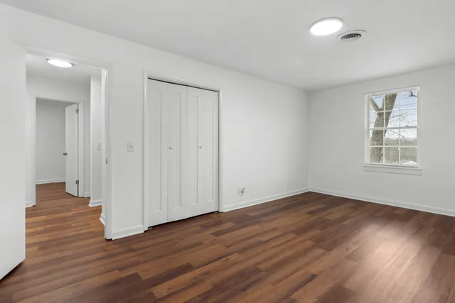 a view of an empty room with wooden floor and a window