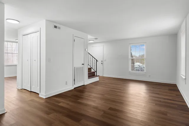 an empty room with wooden floor and windows