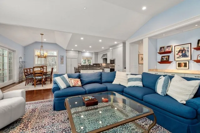 a living room with furniture kitchen view and a chandelier