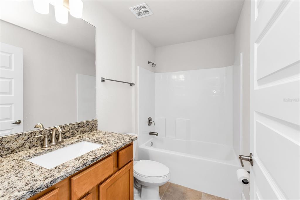 9500 Singer Circle Port Charlotte, FL 33981 - Photo 16 of 60 a bathroom with a granite countertop sink a toilet and shower