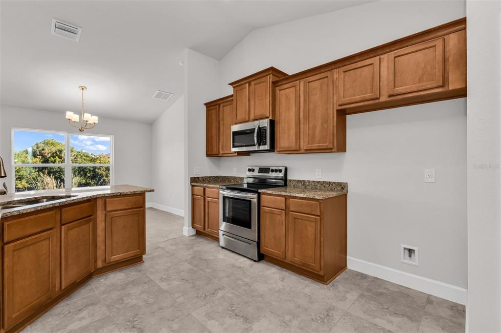 9500 Singer Circle Port Charlotte, FL 33981 - Photo 27 of 60 a kitchen with stainless steel appliances granite countertop a stove a sink and a microwave
