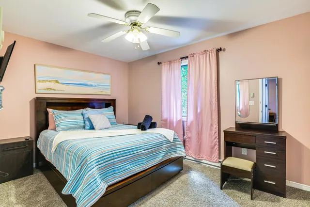 a bedroom with a bed a dresser and a chandelier