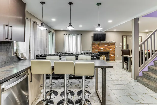 a kitchen with stainless steel appliances kitchen island granite countertop a table chairs and a refrigerator