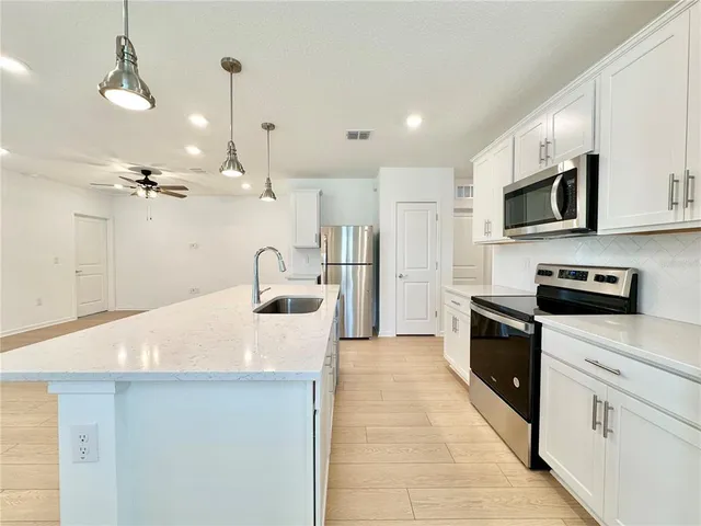 a large kitchen with stainless steel appliances kitchen island a stove a sink a refrigerator and a microwave