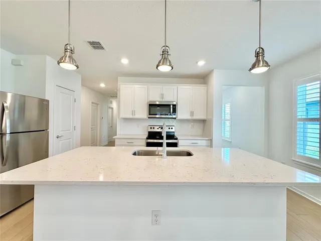 a large kitchen with granite countertop a stove a refrigerator a sink and a refrigerator