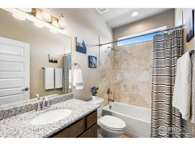 a bathroom with a granite countertop sink a toilet a mirror and shower