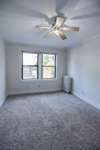 a view of an empty room with window and chandelier fan