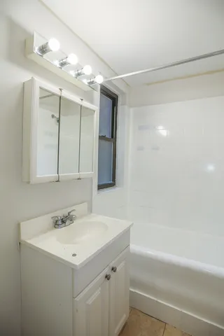 a bathroom with a bathtub a sink a large mirror and vanity