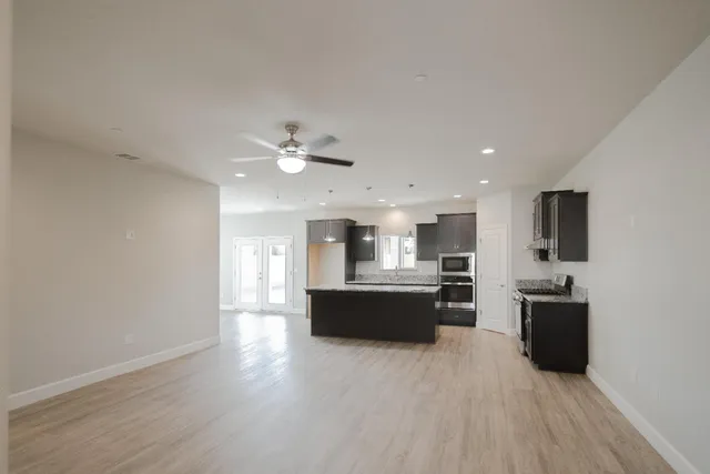 a large kitchen with cabinets wooden floor and stainless steel appliances
