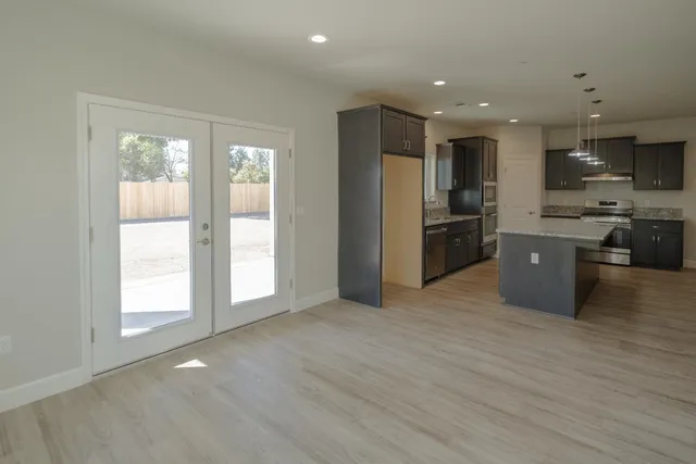 a view of kitchen with stainless steel appliances granite countertop a stove top oven a refrigerator a sink and a large window