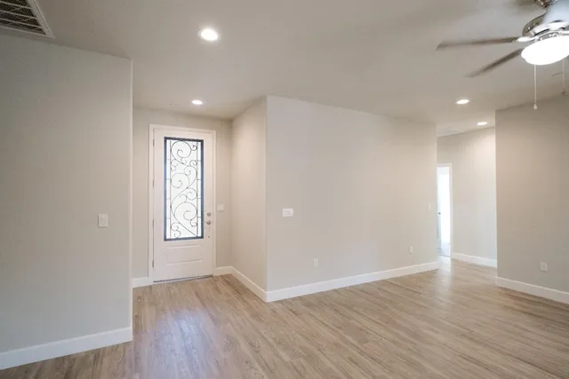 an empty room with wooden floor and windows