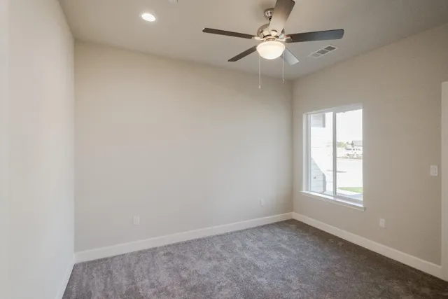 an empty room with windows and ceiling fan
