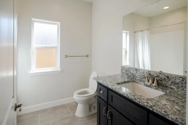 a bathroom with a granite countertop sink a toilet and a mirror