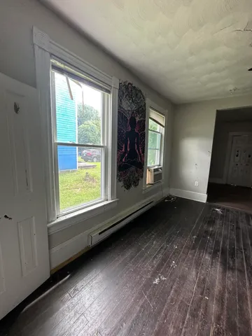 a view of an empty room with wooden floor and a window