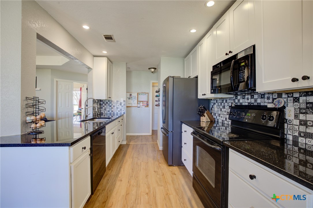 940 Cordova Loop Seguin, TX 78155 - Photo 5 of 32 a kitchen with stainless steel appliances kitchen island granite countertop a refrigerator a stove top oven a sink dishwasher and wooden cabinets with wooden floor