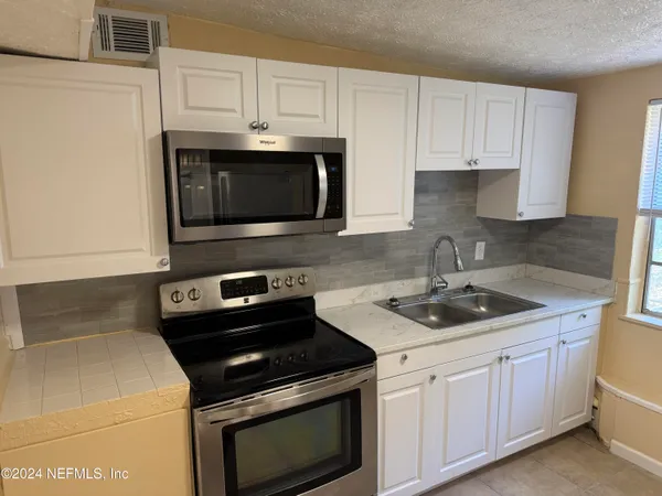 a kitchen with granite countertop white cabinets and stainless steel appliances