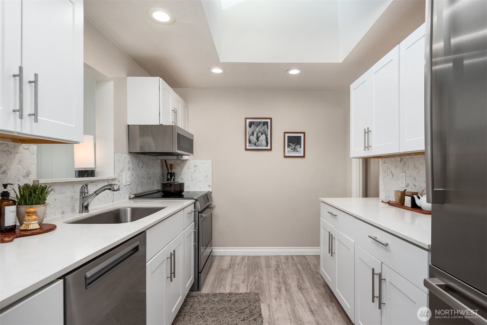 4026 52nd Avenue Southwest Seattle, WA 98116 - Photo 9 of 37 a kitchen with a sink dishwasher stove and white cabinets with wooden floor