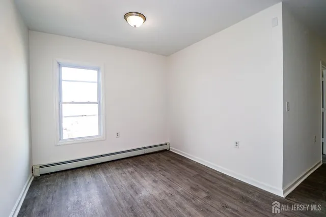 an empty room with wooden floor and window