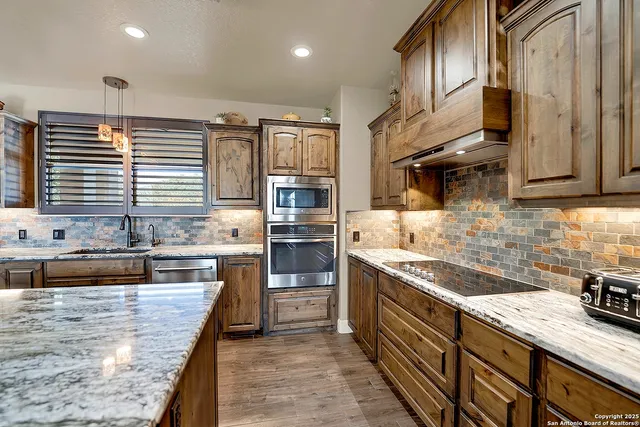 a kitchen with stainless steel appliances granite countertop wooden cabinets a sink dishwasher a stove and a refrigerator