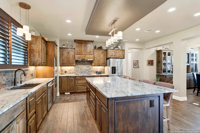 a kitchen with a stove a sink dishwasher and a refrigerator with wooden floor