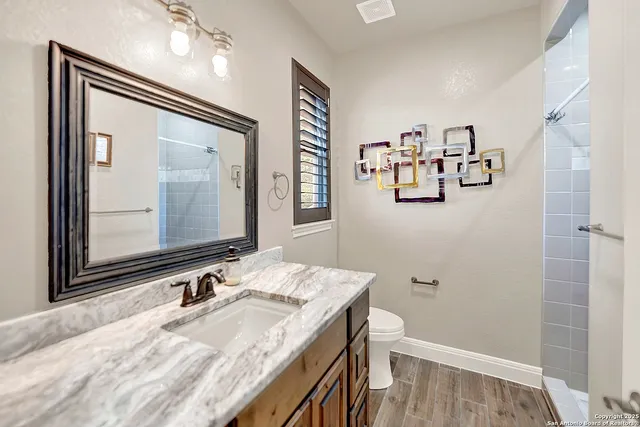 a bathroom with a granite countertop sink a mirror and a shower