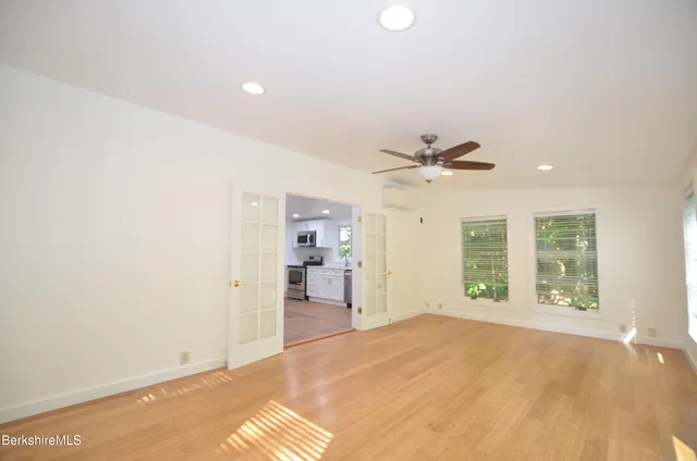 a view of an empty room with window and wooden floor
