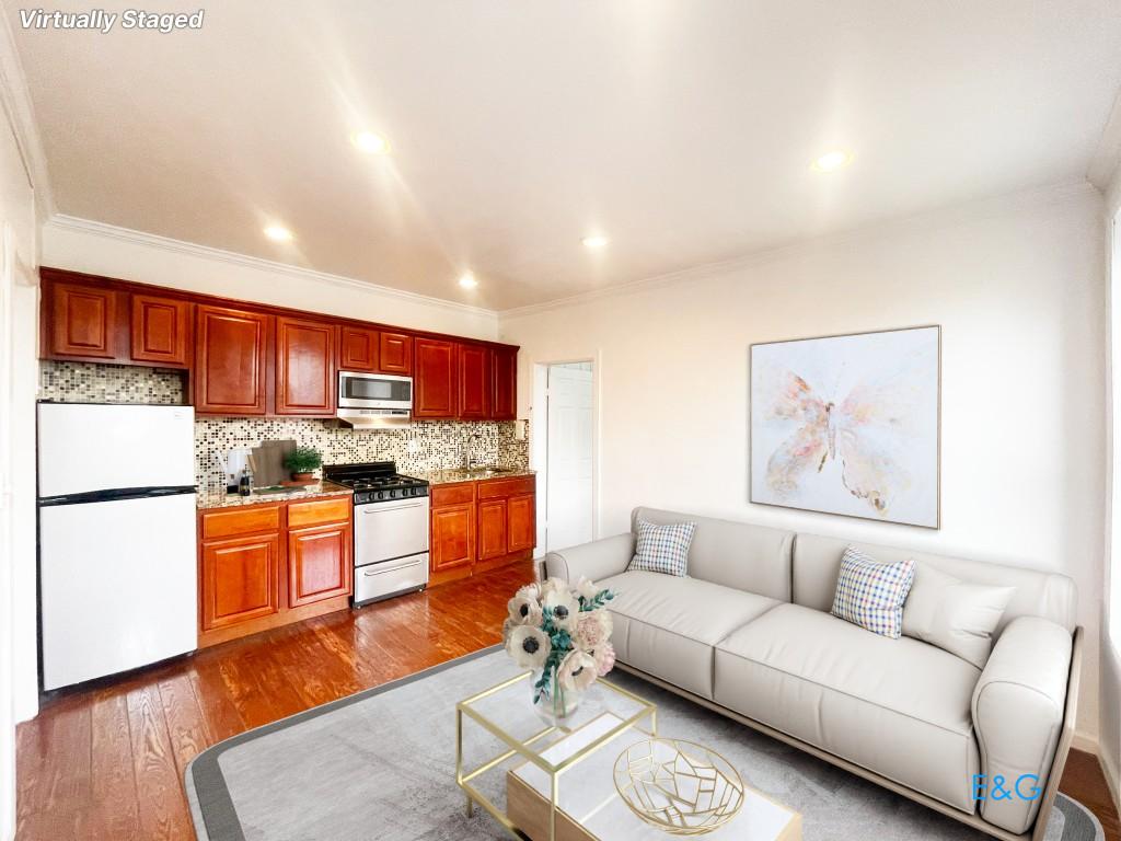 a living room with stainless steel appliances kitchen island granite countertop furniture and a wooden floor