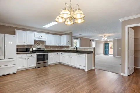a large kitchen with cabinets wooden floor and stainless steel appliances