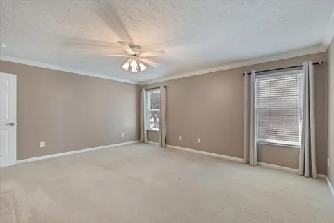an empty room with chandelier fan and windows