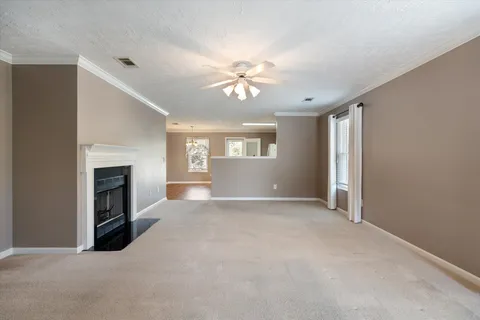 a view of a livingroom with a fireplace ceiling fan and windows
