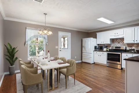 a kitchen with stainless steel appliances kitchen island granite countertop a dining table chairs and refrigerator