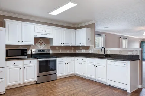 a kitchen with granite countertop white cabinets and a sink