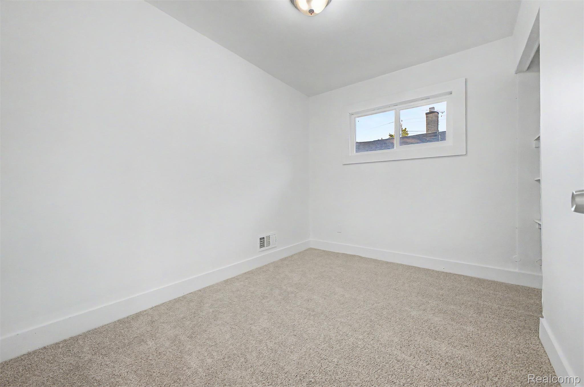 26718 Penn Street Inkster, MI 48141 - Photo 13 of 27 Neutral-toned carpeting complements the white walls and trim, featuring a single window with white framing