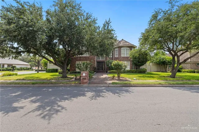 a view of a house with a big yard and large trees