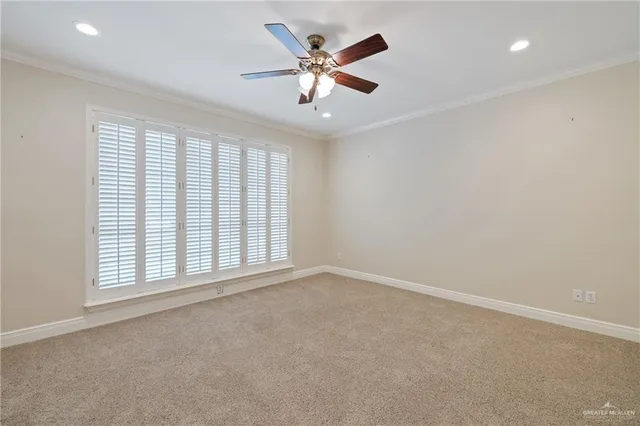 an empty room with chandelier fan and windows
