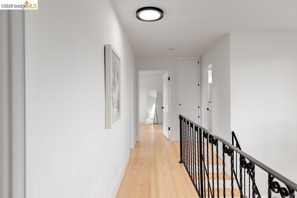 1298 Ribbon Street Foster City, CA 94404 - Photo 43 of 86 Hallway featuring light wood-finish flooring, white walls, and a black wrought iron stair railing