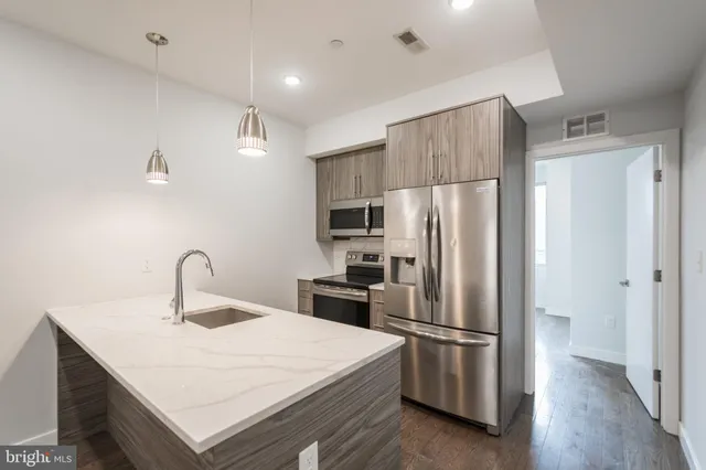 a kitchen with stainless steel appliances a refrigerator a sink a stove a microwave and wooden floor